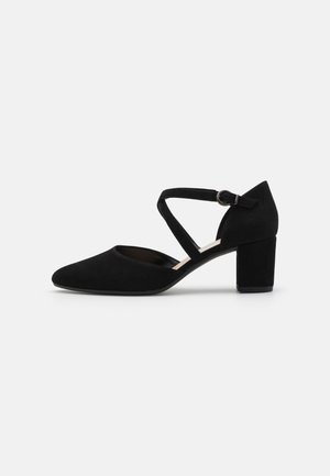 Black suede high heel shoe with a pointed toe, cross strap design, and a chunky heel. Smooth texture with no visible patterns or accents.