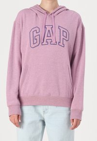 Fioletowa bluza z kapturem z kieszenią, ściągaczami przy rękawach i w pasie. Posiada logo "GAP" w ciemniejszym odcieniu fioletowego. Wykonana z miękkiej, strukturalnej tkaniny.