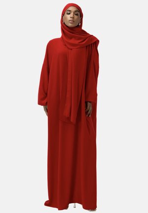 Robe rouge longue et fluide en tissu léger, avec des manches larges et une écharpe assortie drapée sur les épaules.