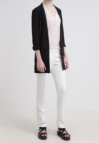 Svart lättviktsblazer, mjuk rosa v-ringad topp, vita välsittande byxor och svarta remsandaler med plattform, med upprullade ärmar och minimal hårdvara.
