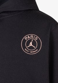 Felpa nera con un motivo testurizzato, caratterizzata da un logo circolare rosa con il testo "PARIS" e "SAINT-GERMAIN" e un simbolo silhouettato.