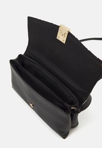 Borsa in pelle nera con fibbia in metallo dorato, dotata di un ampio interno in tessuto nero con due scomparti e tracolla.