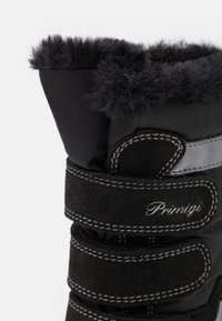 Svarta vinterstövlar med en mjuk syntetpäls-krage, tillverkade av mocka och textilmaterial, säkrade med justerbara remmar och med silverfärgade sömnadsdetaljer.