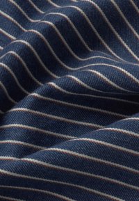 Tissu bleu avec des rayures horizontales blanches et rouges, présenté en plis doux avec un détail de texture en gros plan.