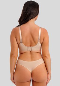 Nude prádlo set složený z hladké, pružné tkaniny. Podprsenka má nastavitelné ramínka a zapínání se třemi háčky na zadní straně; kalhotky mají nízký střih.