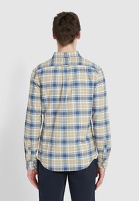 Geruit overhemd met blauwe, beige en witte vierkanten; knoopjesmanchetten; traditionele kraag; zachte katoenen stof; gebogen onderkant.