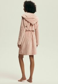 Różowy szlafrok z kapturem o fakturze fal, wykonany z miękkiego materiału. Otwarty z przodu, z paskiem w talii, długość do połowy uda.