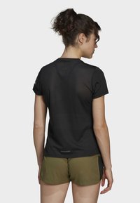 T-shirt de sport noir avec une texture en maille, à manches courtes et col rond, associé à un short vert olive.