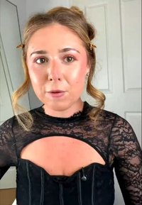 Top in pizzo nero con collo alto e un'apertura sul petto, abbinato a un capo intimo nero strutturato con cuciture verticali.