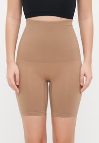 Pantaloni corti beige a vita alta realizzati in materiale elastico, con una superficie liscia e una vita elastica, progettati per comfort e supporto.