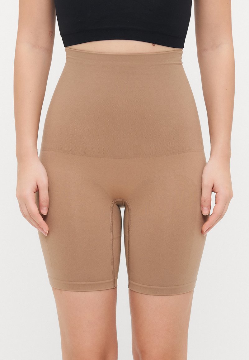 Pantaloni corti beige a vita alta realizzati in materiale elastico, con una superficie liscia e una vita elastica, progettati per comfort e supporto.