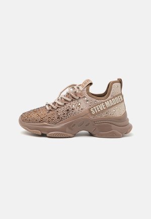 Baskets marron épaisses avec ornements en strass, lacets à l'avant, et logo "Steve Madden" sur le côté et sur la languette du talon.