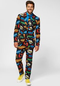 Colorful comic-print suit featuring black background with bright phrases and graphics. Includes a blue shirt and yellow sneakers.
