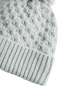 Bonnet en tricot gris clair avec un motif en losange texturé et un bord côtelé. Fil doux avec un sommet arrondi et un détail en pompon.