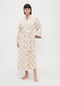 Pikk kreemjas hommikumantel, millel on beež geomeetriline muster, vööga talje kohal, laiad varrukad ja pehme tekstuur.