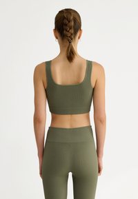 Ärmgarderad sport-bh i olivgrönt med matchande högmidjade leggings. Har en fyrkantig rygg och ett texturerat tyg med en tajt passform.