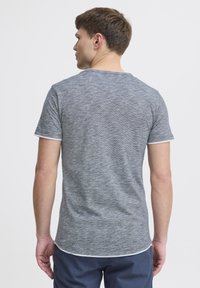 Tricou scurt de culoare gri deschis, cu mâneci scurte, având un model texturat, margine rotundă și umplutură albă la manșete. Viziunea din spate arată un design ajustat.