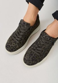 Sneaker mit Leopardenmuster in dunklen Grün- und Schwarztönen. Sie verfügen über graue Schnürsenkel, einen gepolsterten Schuhkragen und eine hellfarbige Gummisohle.