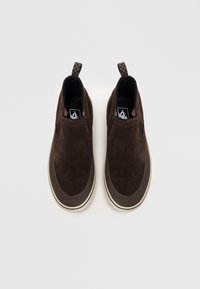 Brune semskede slip-on sko med gummisåle, elastiske side detaljer og et ternet pull-tab. Glat tekstur med kontrasterende mørkebrune detaljer.