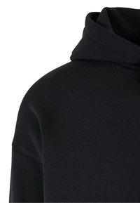 Sudadera negra con un tejido suave y texturizado. Presenta una capucha amplia y hombros sin costuras, ofreciendo un ajuste relajado y un diseño minimalista.