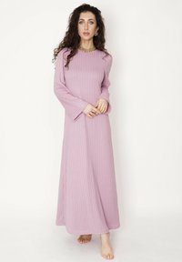 Długa różowa sukienka z żeberkowanym wzorem i długimi rękawami, z okrągłym dekoltem i bocznymi rozcięciami dla ułatwienia ruchów. Miękka tekstura, sięgająca do ziemi.