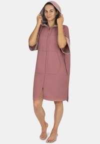 Häkeliger pinker Bademantel mit einem strukturierten Waffelstrickdesign. Verfügt über einen Frontreißverschluss, kurze Ärmel und ein gesticktes Logo. Zwei Seitentaschen.