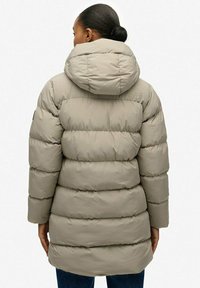 Chaqueta de plumas de color beige claro con capucha, con secciones acolchadas horizontales, bolsillos laterales con cremallera y una tela texturizada.