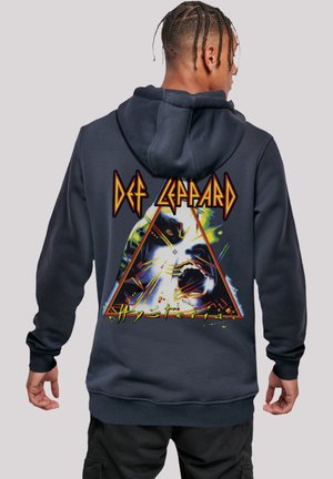 Dunkelblaues Kapuzen-Sweatshirt mit einem grafischen Design auf der Rückseite, das ein Dreieck, farbenfrohe Akzente und den Text "Def Leppard Hysteria" zeigt.