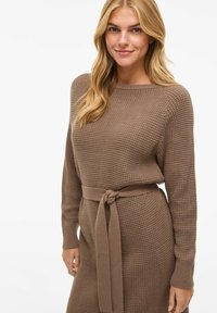 Brązowa dzianinowa sukienka z teksturowanym wzorem, długimi rękawami i pasem wiązanym w talii. Miękka tkanina, luźny krój i okrągły dekolt.