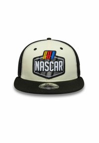 Gorra snapback crema y negra con visera plana. Presenta un logo de NASCAR bordado en el centro, con coloridas franjas de carreras arriba.