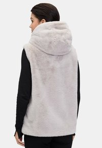 Kamizelka polarowa w jasnoszarym kolorze z dużym kapturem, bez rękawów i miękką teksturą. Posiada prosty dół i boczne rozcięcia dla komfortu.