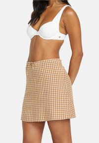 Falda a cuadros marrón y crema con cintura ajustable, hecha de tela ligera, con corte recto y textura suave.