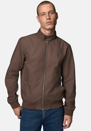 Rudas zip-up bomber striukė su stovinčia apykakle, elastingomis rankovėmis ir šoninėmis kišenėmis. Lygus paviršius ir minimalistiškas dizainas.