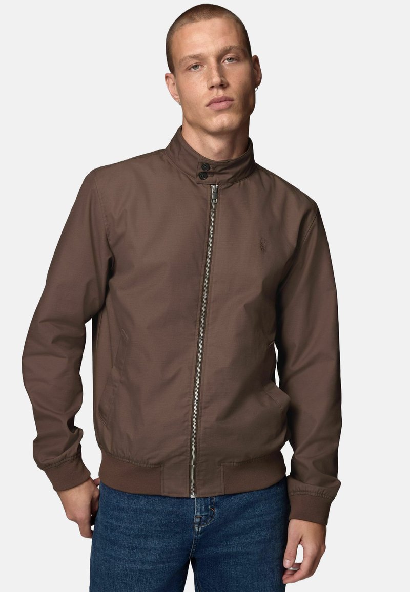 Veste bomber zippée marron avec col montant, poignets élastiques et poches latérales. Texture lisse et design minimaliste.