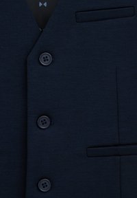 Tengerész kék mellény texturált anyagból, lehasított gallérral, négy fekete gombbal és egy mellzsebbel.