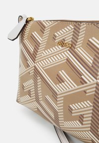 Guess-Handtasche mit einem geometrischen Muster in Beige- und Brauntönen, verziert mit einem goldfarbenen Logo und einer glatten Textur. Reißverschlussverschluss mit Griff.