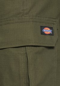 Olivově zelená tkanina s jemnou mřížkovou strukturou, obsahující náprsní kapsu a všitou cedulku s logem Dickies na boku.