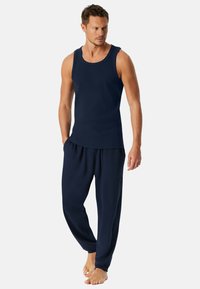 Marineblauwe tanktop en bijpassende losse broek van zachte stof, met een eenvoudig ontwerp zonder zichtbare patronen of accenten.