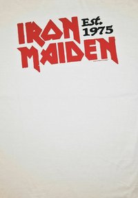 Bílá bavlněná tričko s tučným červeným a černým nápisem "IRON MAIDEN" a "Est. 1975" v grafickém stylu. Hladká textura.