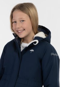 Námořnická modrá bunda s kapucí má měkkou bílou fleecovou podšívku. Obsahuje malé logo deštníku a text loga na rukávu.