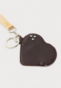 Πορτοφόλι μπρελόκ σε σχήμα καρδιάς, από σκούρο καφέ δέρμα με ασημένια μεταλλικά στοιχεία, που διαθέτει τρεις μικρές ασημένιες καρδιές και λουράκι με υφή.