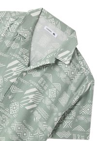 Camicia a maniche corte di colore verde chiaro con motivi geometrici bianchi. Caratterizzata da un colletto e una chiusura con bottoni, realizzata in tessuto testurizzato.