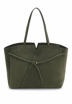 Sac cabas en daim vert olive avec deux poignées, bord supérieur découpé et sangle tressée nouée à l'avant pour la décoration.