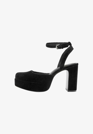 Svarta mockaskor med platå och en tjock blockklack, justerbart vristband och rundad tådesign. Slät textur och minimalistisk stil.