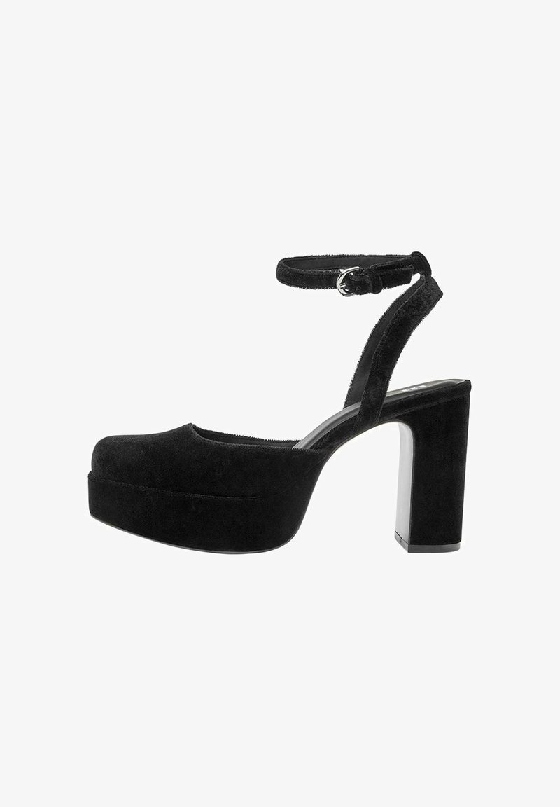 Musta mokkanahka korkokenkiä paksulla lohkopohjalla, säädettävällä nilkkaremmillä ja pyöreällä kärjellä. Suoraviivainen rakenne ja minimalistinen tyyli.