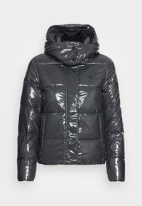 Czarna, błyszcząca kurtka puchowa z wysokim kołnierzem, zapięciem na guziki i pikowanym wzorem. Posiada logo na lewym piersi oraz luźny krój.