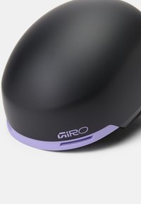 Μαύρο κράνος με ομαλή, στρογγυλή μορφή και ματ φινίρισμα, με μια αντίθετη μωβ λεπτομέρεια στη βάση και ένα λευκό λογότυπο.