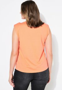 Korte mouwen, ronde hals t-shirt in een levendige koraalkleur. Zachte, gladde textuur met een subtiele stretch. Klassieke pasvorm, rechte zoom, minimalistisch ontwerp.