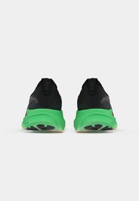 Scarpe da corsa nere e verdi con una tomaia testurizzata, design elegante, accenti a contrasto e una robusta suola in gomma nera.