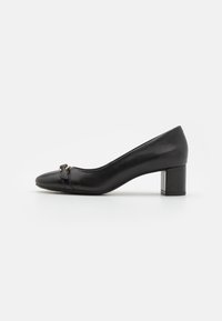 Escarpin en cuir noir avec un bout pointu, doté d'une petite sangle décorative à l'avant et d'un talon carré robuste. Texture lisse.
